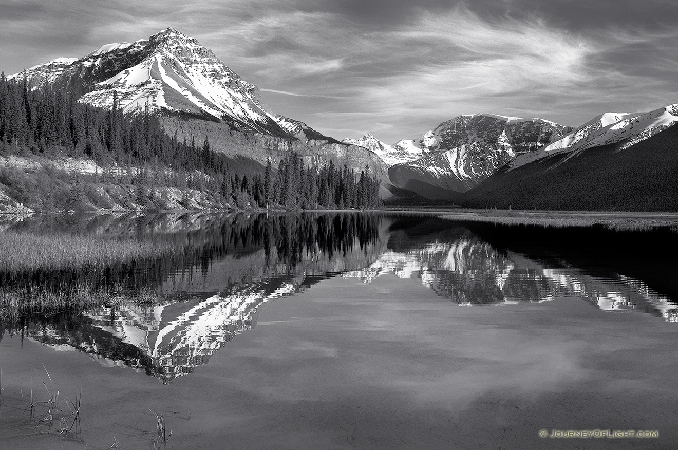 Only a small ripples disturbs the reflection of the mountains in the distance. - Canada Picture