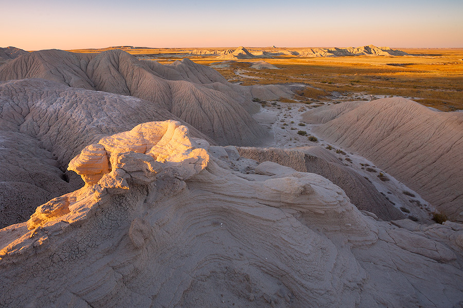 As the sun sets warm sunlight bathes parts of Toadstool Geologic Park in warm hues. - Toadstool Geologic Park Photography