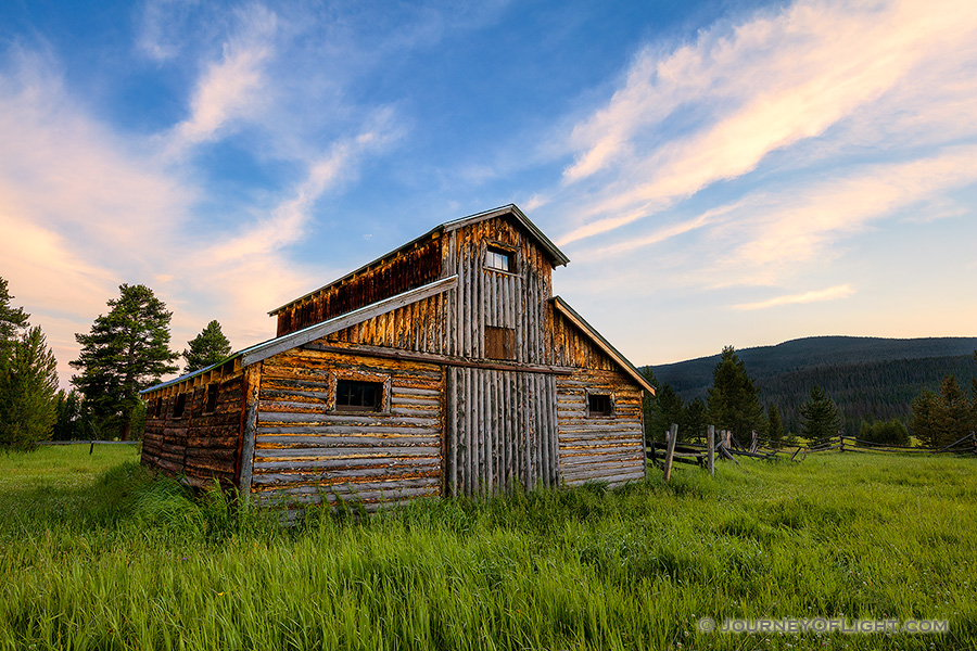 A beautiful wooden barn sits in the Kawuneeche Valley on the western side of Rocky Mountain National Park in Colorado.  Clouds lazily floated by as the sun set behind the Never Summer Range in the distance. - Colorado Photography