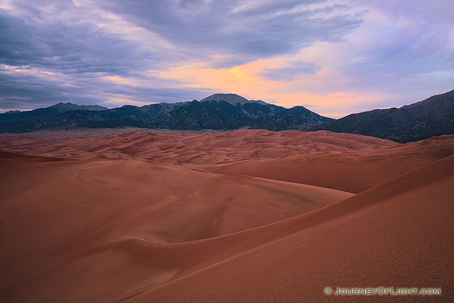 As the last of the light of the day diminishes at Great Sand Dunes National Park, a single set of clouds remain illuminated before quietly going dim. - Colorado Photography