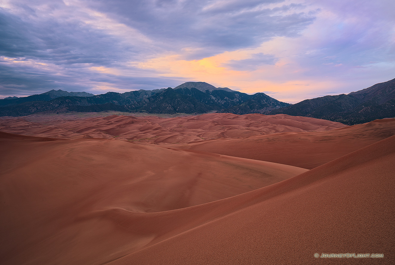 As the last of the light of the day diminishes at Great Sand Dunes National Park, a single set of clouds remain illuminated before quietly going dim. - Colorado Picture