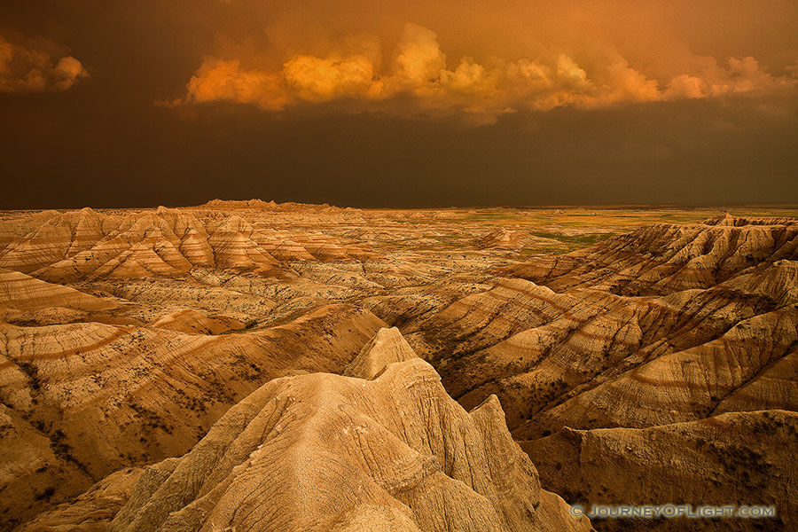 Facing east, the sky was nearly pitch black shrouded by the fierce storm that had just passed through.  As the sun dipped below the horizon the last rays hit the trailing storm clouds and the ambient warm light lit up the valley across the Badlands in South Dakota. - South Dakota Photography