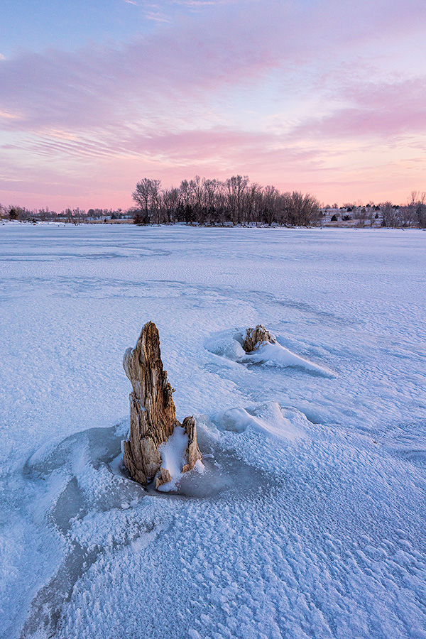 A scenic landscape photograph of purple clouds over the frozen lake at Walnut Creek, Nebraska. - Nebraska Photography