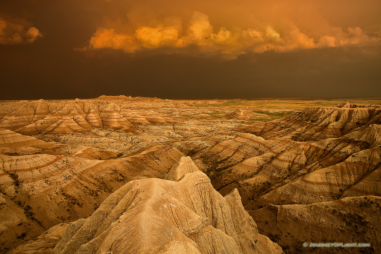 Facing east, the sky was nearly pitch black shrouded by the fierce storm that had just passed through.  As the sun dipped below the horizon the last rays hit the trailing storm clouds and the ambient warm light lit up the valley across the Badlands in South Dakota. - South Dakota Picture