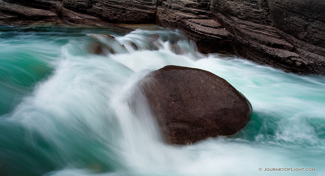 A lone rock holds against the rush of the water at Maligne Canyon in Banff National Park, Alberta, Canada. - Banff Picture